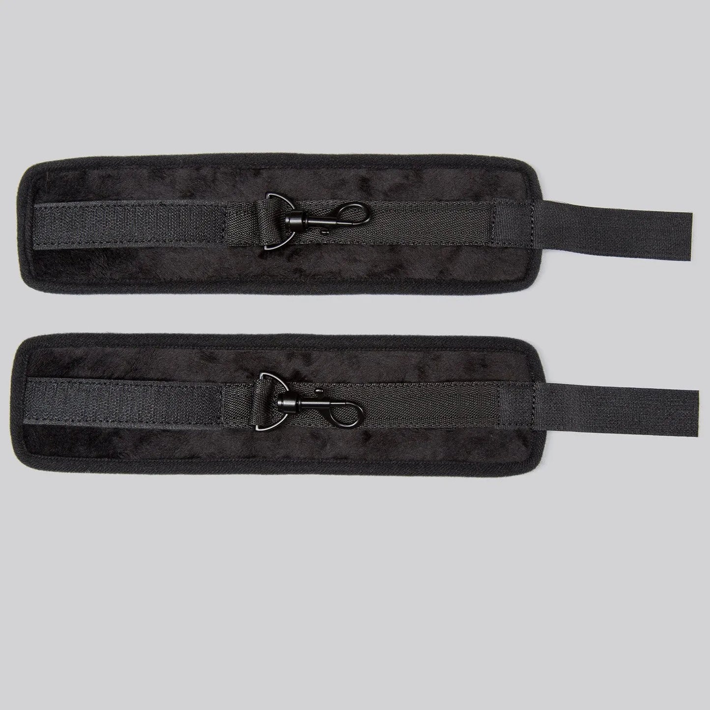 Adjustable black ankle cuffs with soft padding and metal lock connector between the cuffs.