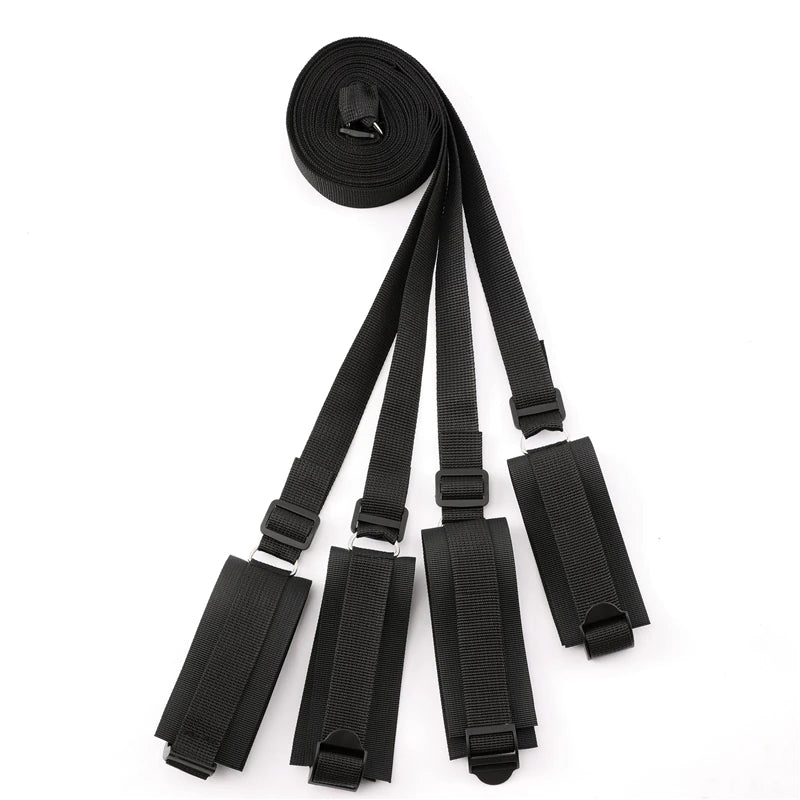 Black adjustable bed restraint kit with under-mattress anchor system and four padded restraint cuffs.
