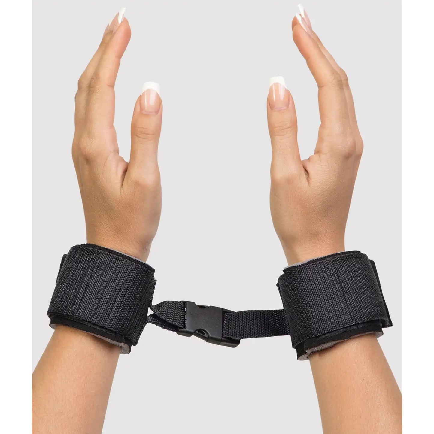 Adjustable wrist restraint cuffs connected with a quick-release buckle and soft padded lining.
