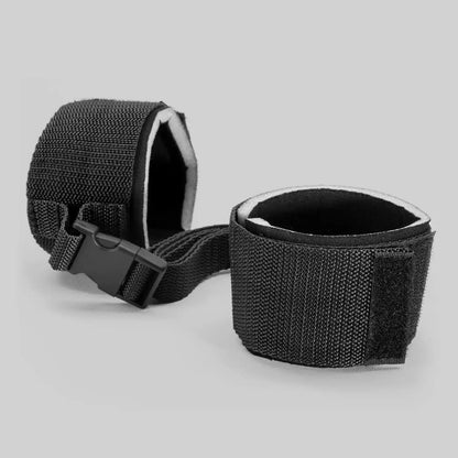Adjustable wrist restraint cuffs connected with a quick-release buckle and soft padded lining.
