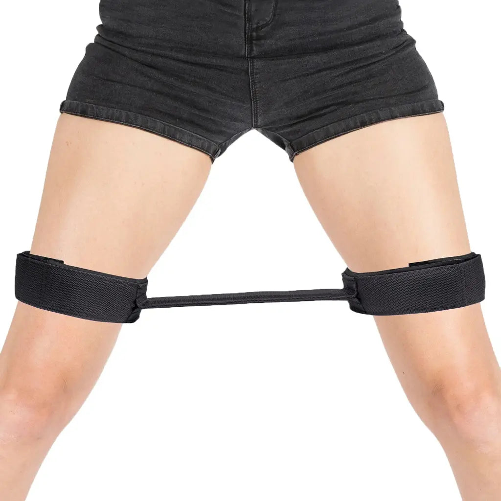 Black adjustable thigh restraint strap with flexible connector and padded leg cuffs.