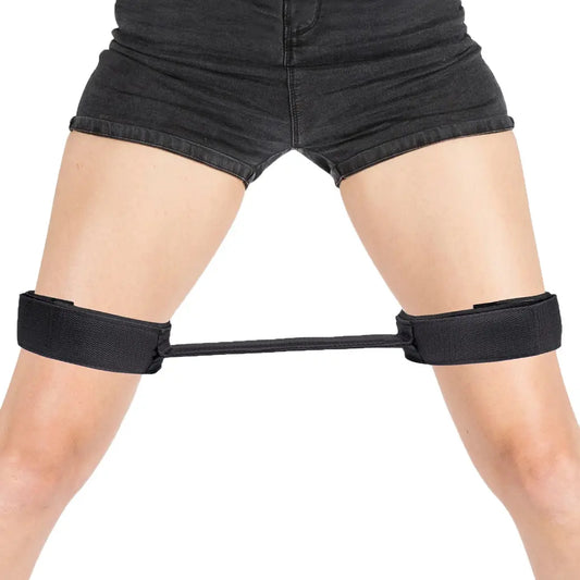 Black adjustable thigh restraint strap with flexible connector and padded leg cuffs.