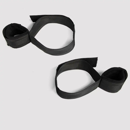  Black wrist-to-thigh restraint set with adjustable wrist cuffs and thigh straps connected by nylon webbing.