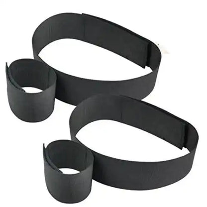 Black wrist-to-thigh position restraint strap with adjustable wrist cuffs and leg positioning straps.