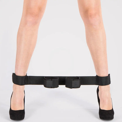 Black wrist-to-ankle position restraint strap with adjustable padded wrist and ankle cuffs connected by durable nylon webbing.