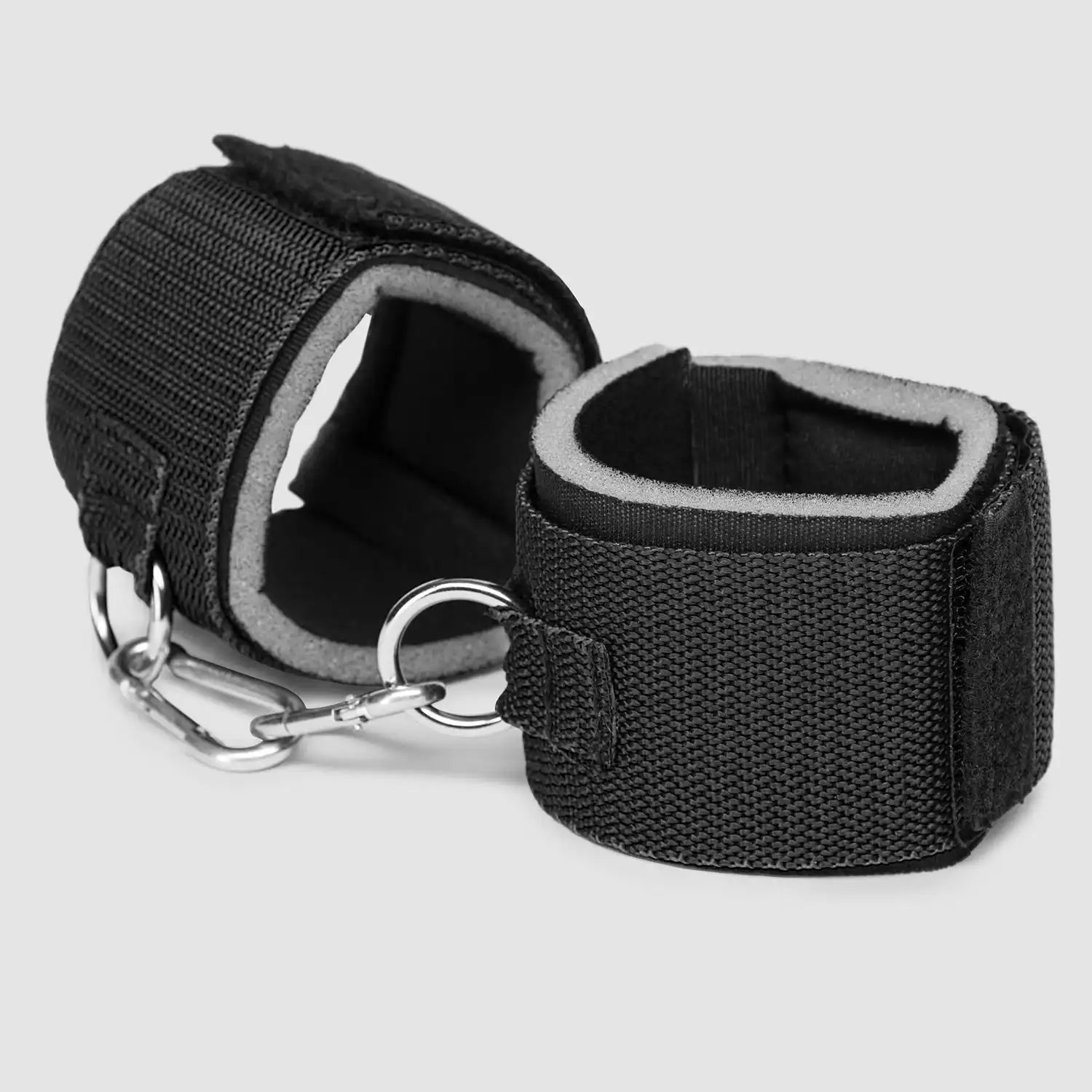 Black wrist-to-waist restraint set with adjustable waist belt, padded wrist cuffs, and metal clip connectors.